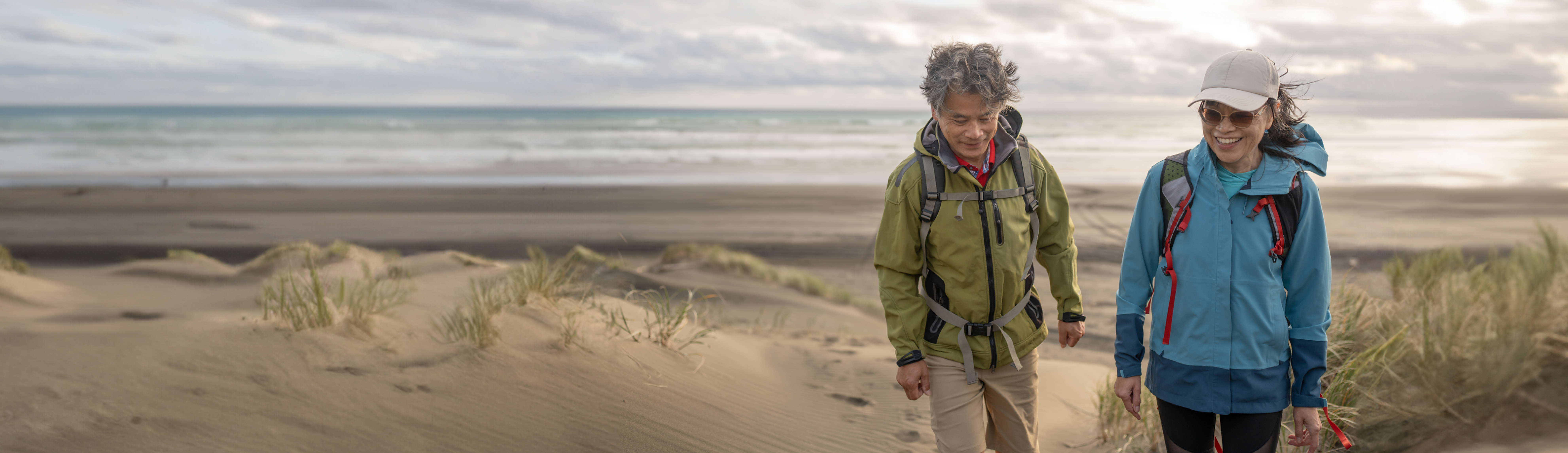 couple walking in windbreaker coats on the beach
